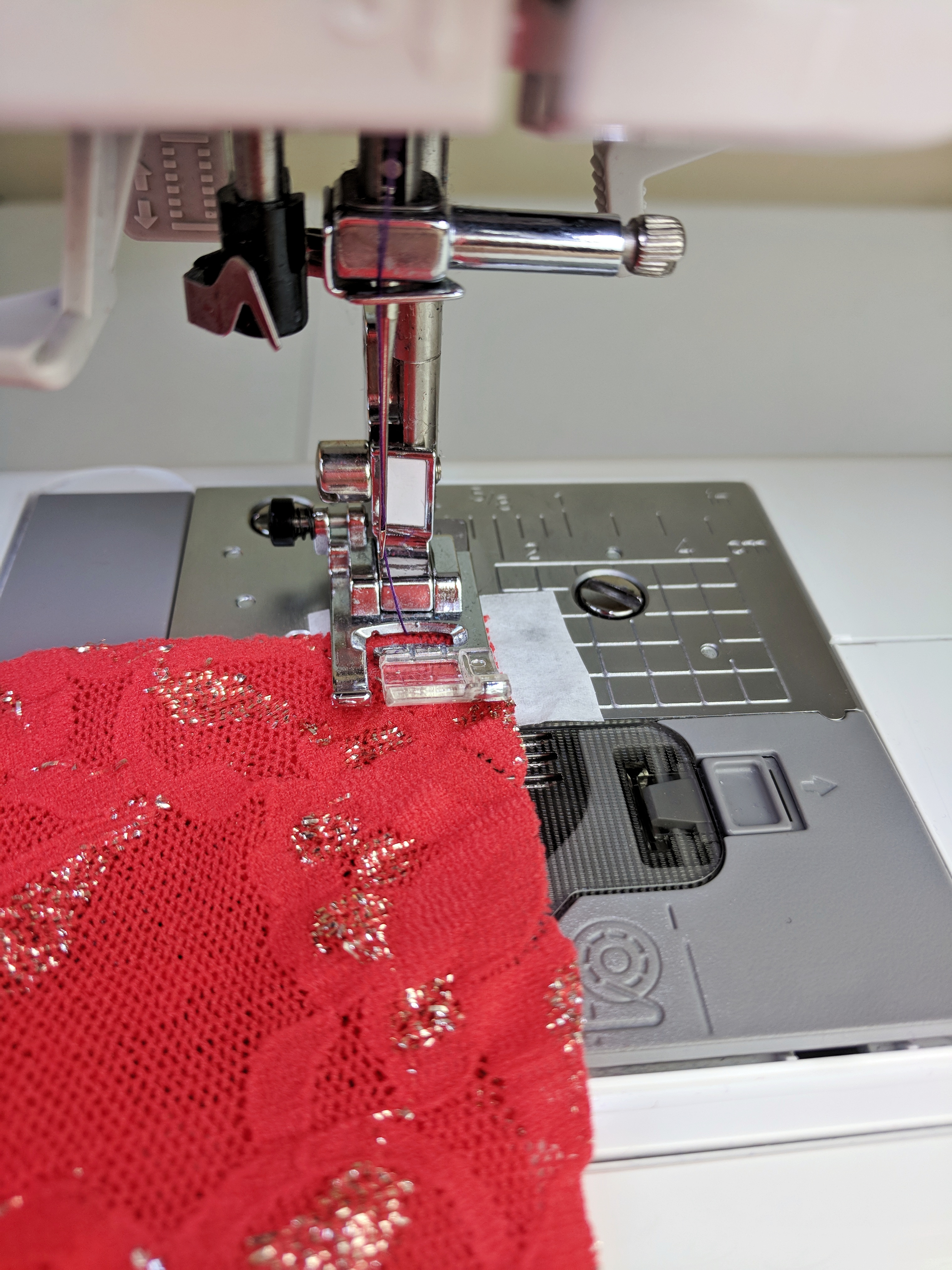 Papel de tecido debaixo das rendas na máquina de costura.