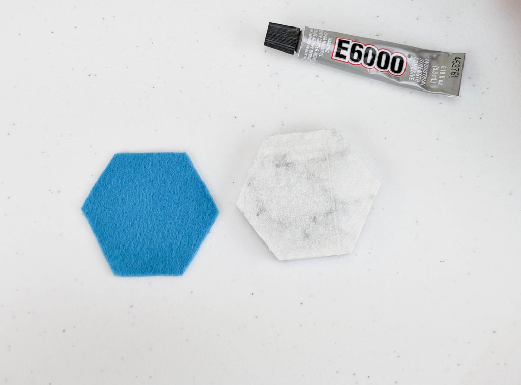 Felt hexagon next to tile, with a glue bottle laying above them