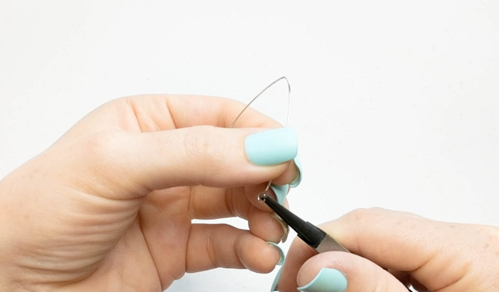 pliers being used to open a loop on an earring.