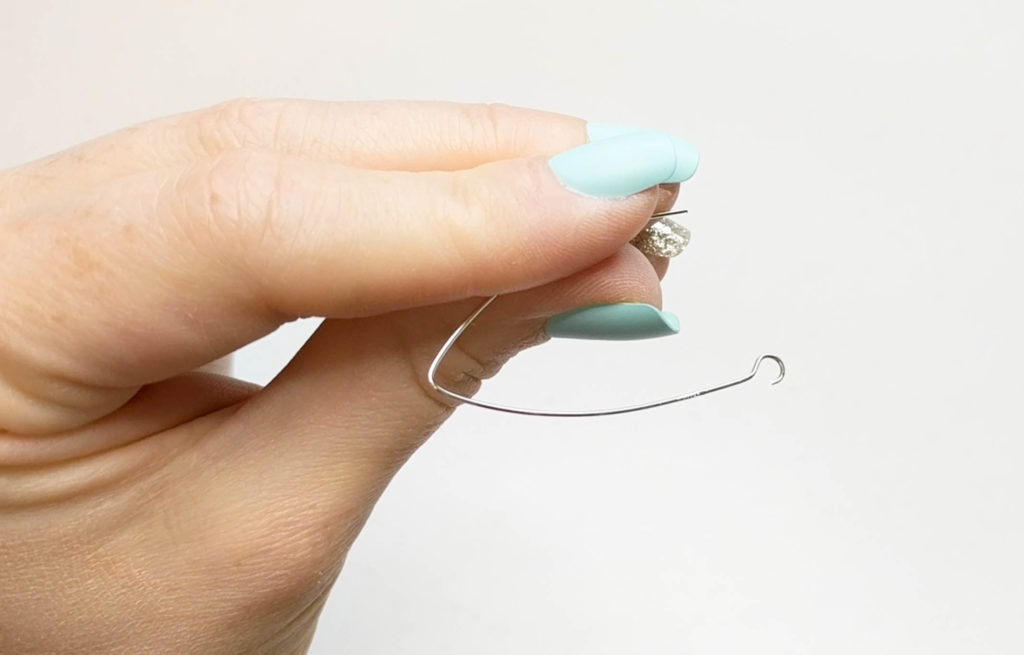 earring being shown with the loop opened making a hook on the end of the earring.