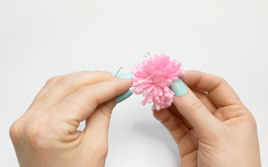 Pom pom about to be strung onto an earring.
