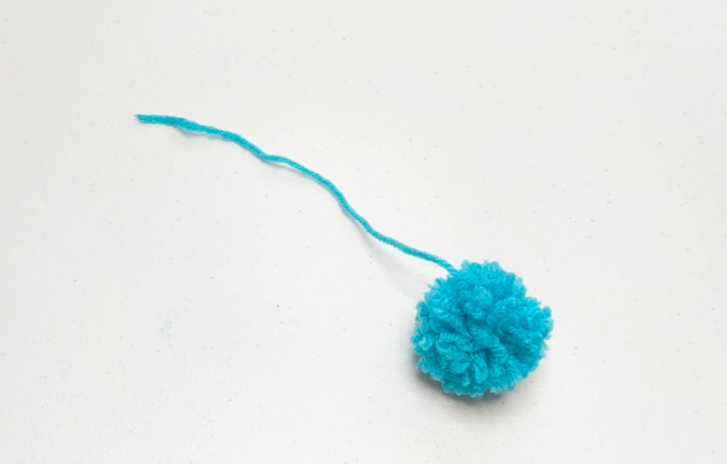 blue pom pom with one long string coming from it.