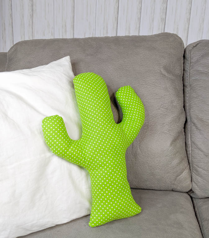 Cactus pillow on a gray couch with a white throw pillow.
