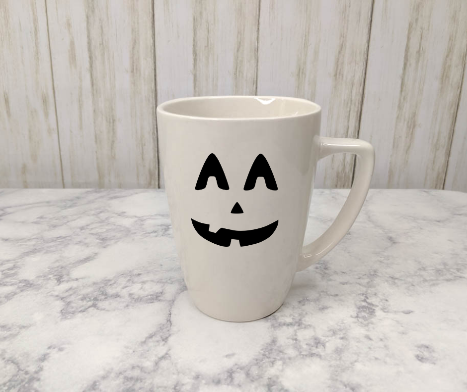 White mug with a black jack-o-lantern face on it.