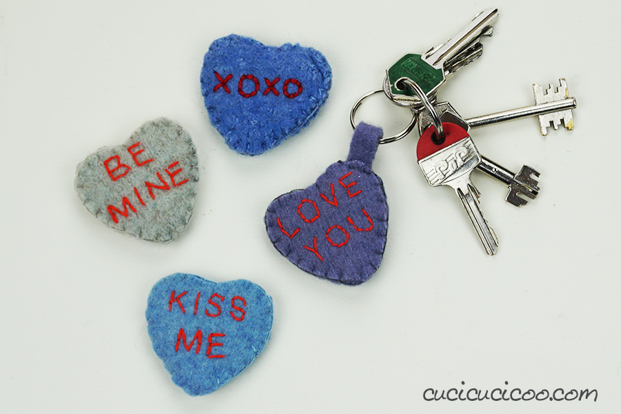 Four heart key chains that are sewn to look like conversations hearts.
