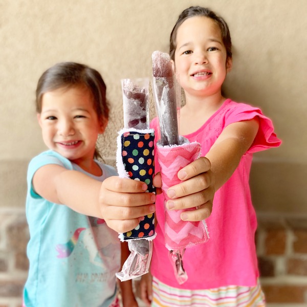little girls holding otter pops that have a fabric holder on the outside.