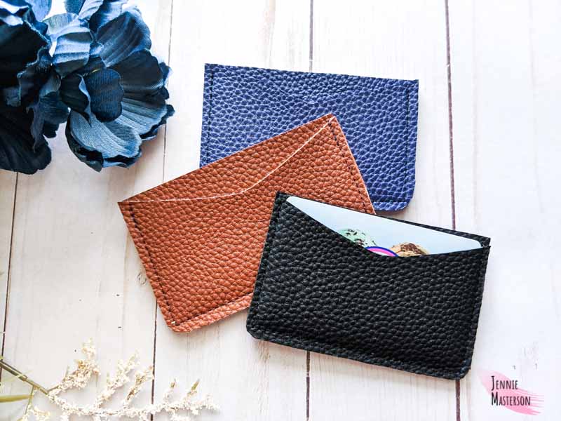 Three card wallets made from faux leather in black, brown and navy colors.