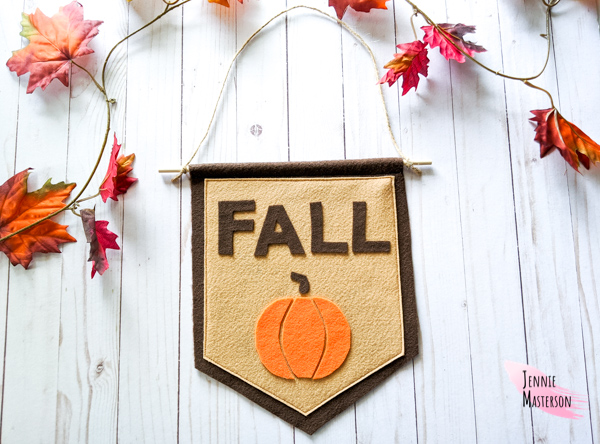 Fall sign made from felt reading "fall" with an image of a pumpkin.