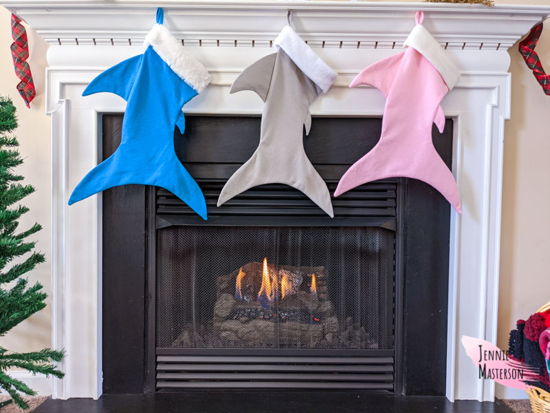 three shark stockings hung over a fireplace.