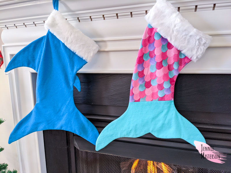 shark stocking and mermaid stocking hung over a fireplace.