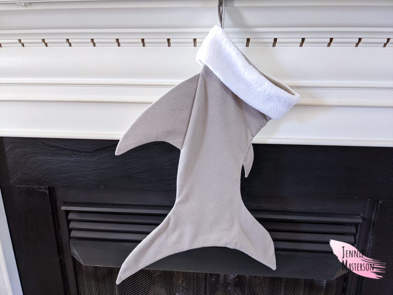 Gray shark stocking hung over a fireplace.