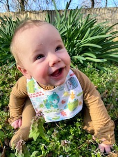 Baby boy wearing a bib and a big grin.