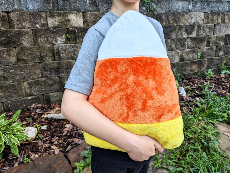 Little boy holding a candy corn plushie.