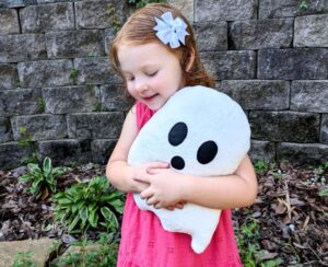 Little girl holding a white ghost plushie.