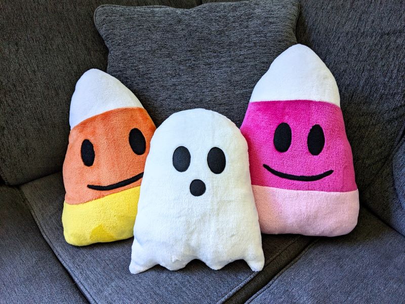 Glost plushie sitting on a couch with two candy corn plushies.