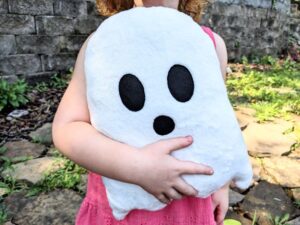 little girl holding a white ghost plushie in her arms.