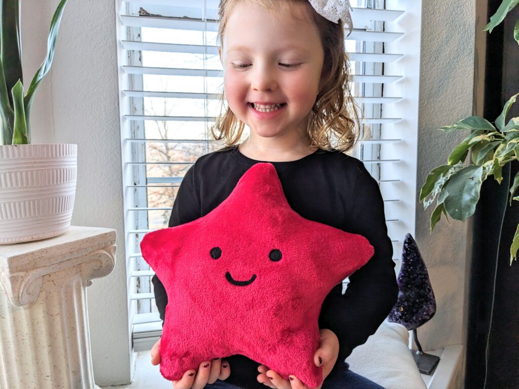 Little girl holding a red star plushie