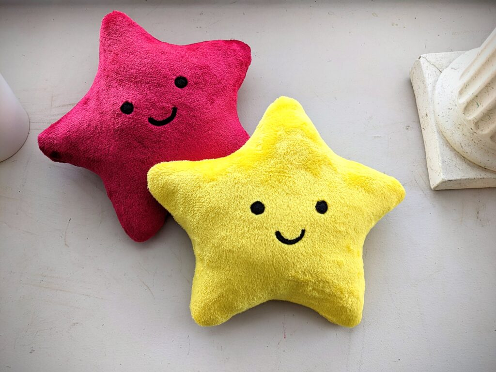 Two star plushies on top of each other. One red and one yellow.