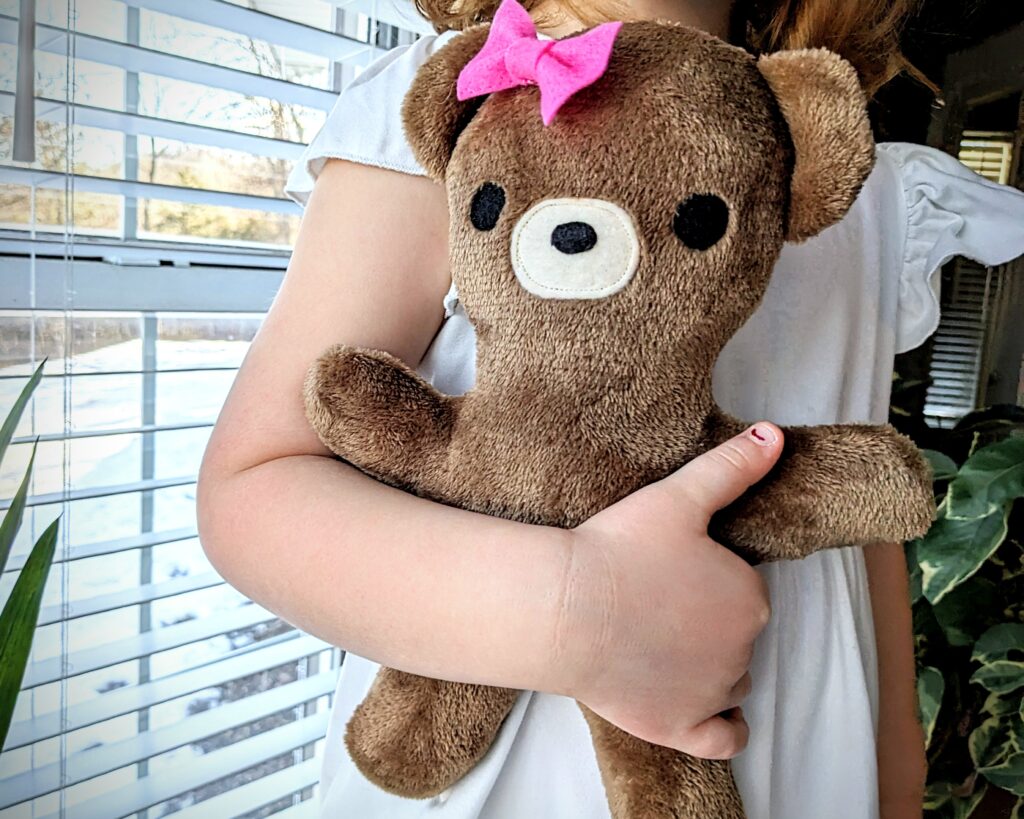 bear plushie being held by a little girl.