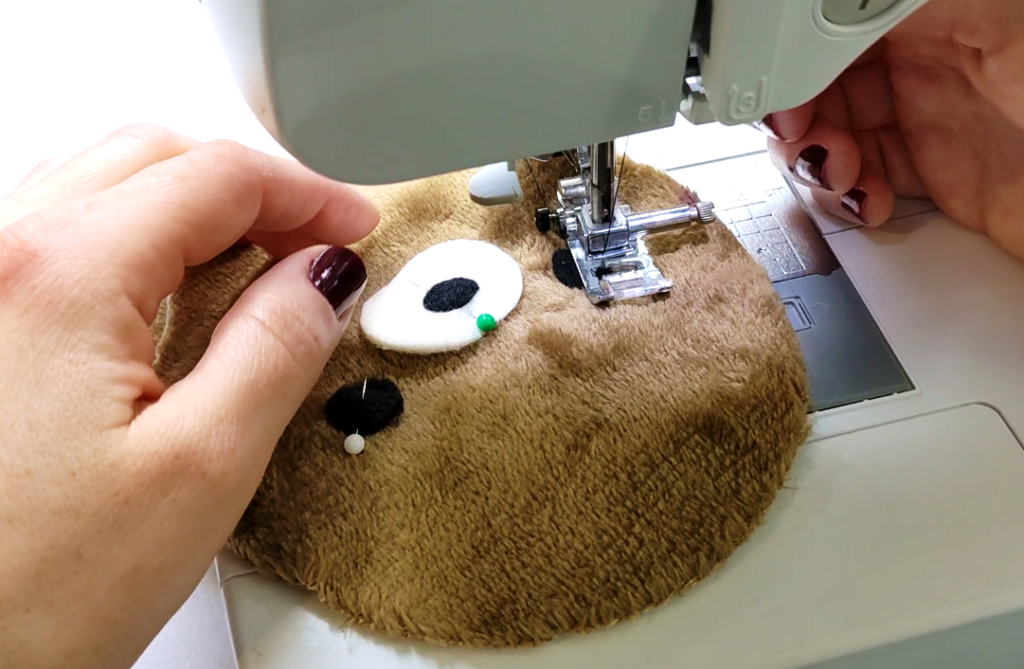 bear plushie face being sewn on