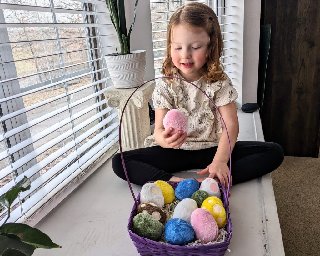 little girl playing with egg plushies